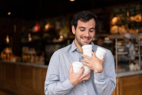 very happy man juggling with cups of coffees and leaving a cafe - junk food stock pictures, royalty-free photos & images