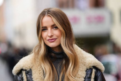Victoria Magrath wears a dark gray ribbed wool turtleneck pullover, a black shiny leather with beige sheep fur details oversized aviator coat,...