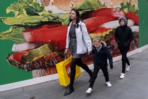 Visitors and tourists come to enjoy the bustle of Leicester Square during a half term break interact with a large scale hoarding covering the...