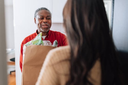 volunteer delivering food for senior man - food stock pictures, royalty-free photos & images