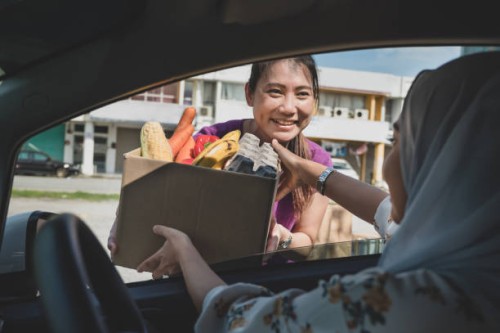 volunteers hands out food at drive through food bank - food stock pictures, royalty-free photos & images