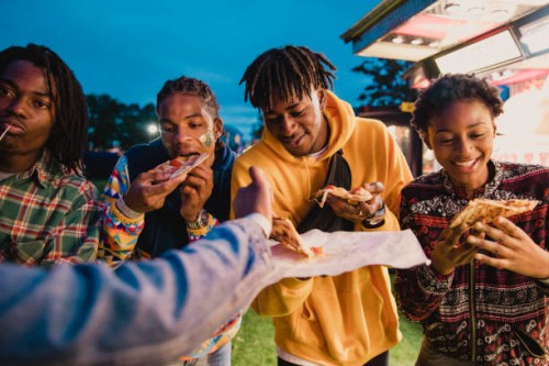 vrienden delen pizza op festival - junk food stockfoto's en -beelden