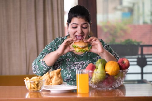 vrouw eten een fast food hamburger - food stockfoto's en -beelden