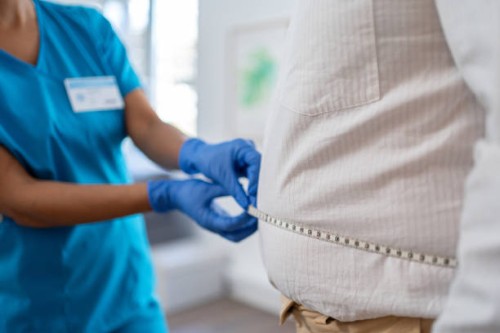 waist measurement in medical practice. the nurse is using a tape measure - junk food stock pictures, royalty-free photos & images
