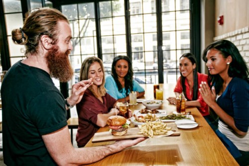 waiter serving foods to friends at table in bar - junk food stock pictures, royalty-free photos & images