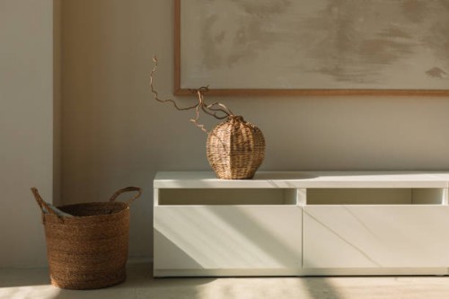 wicker vase on a sideboard below a picture frame and basket in a living room - home decoration stock pictures, royalty-free photos & images