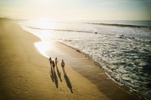 wide aerial shot of family walking on tropical beach at sunrise - travel stock-fotos und bilder