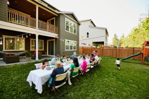 wide shot family sharing a meal in backyard during birthday party - garden decoration stockfoto's en -beelden