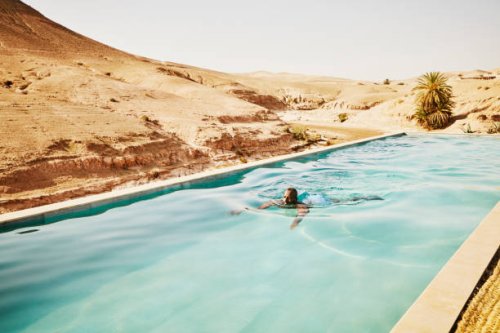 wide shot man swimming in pool at moroccan desert camp during vacation - travel stock pictures, royalty-free photos & images