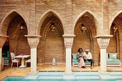 wide shot of couple holding hands while sitting in courtyard of luxury hotel - travel stock pictures, royalty-free photos & images