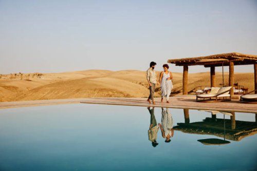 wide shot of couple walking around pool at desert camp at sunrise - travel stock pictures, royalty-free photos & images