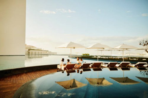 wide shot of family hanging out on lounge chairs by pool at resort - travel stock pictures, royalty-free photos & images