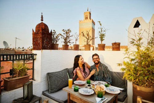 wide shot of laughing couple dining at rooftop restaurant in marrakech - travel stock pictures, royalty-free photos & images
