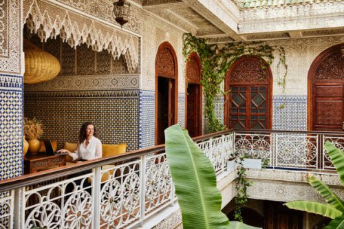 wide shot of mature woman working on laptop in riad during vacation - travel stock pictures, royalty-free photos & images