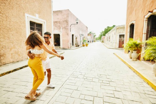 wide shot of smiling couple dancing in street while exploring town during vacation - travel stock pictures, royalty-free photos & images