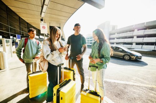 wide shot of smiling family waiting at airport curb for rideshare pickup - travel stock pictures, royalty-free photos & images