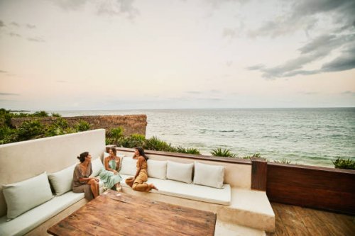 wide shot of smiling female friends relaxing on deck of luxury hotel suite at sunset - travel stock pictures, royalty-free photos & images