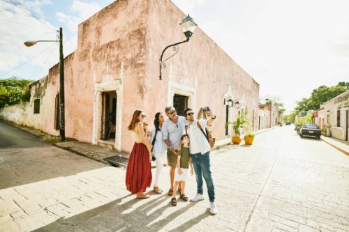 wide shot of smiling multigenerational family taking selfie in street while exploring town during vacation - travel stock pictures, royalty-free photos & images