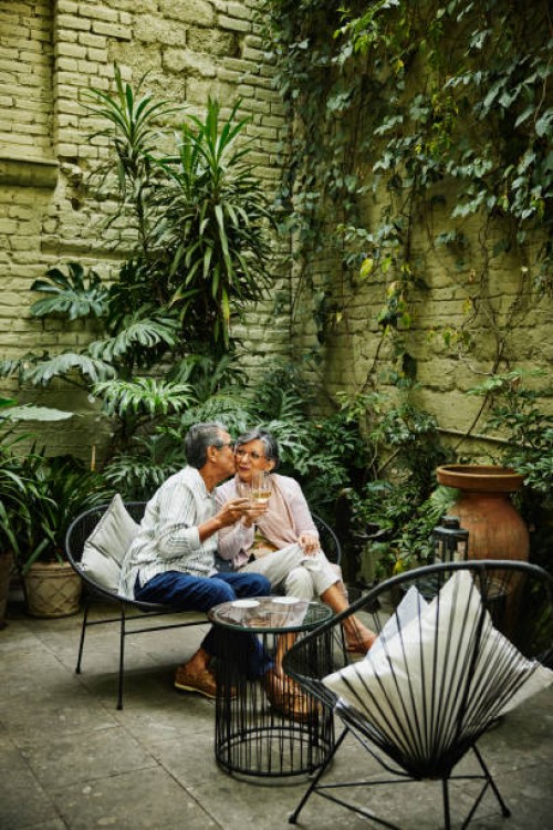 wide shot senior couple kissing in garden of luxury boutique hotel - garden decoration photos et images de collection