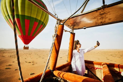 wide shot woman taking selfie during sunrise hot air balloon ride - travel stock-fotos und bilder