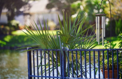 wind chimes next to a metal fence surrounded by lush greenery - garden decoration stock pictures, royalty-free photos & images