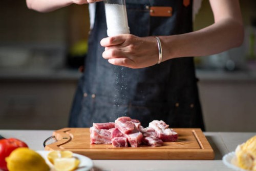 woman adding salt on slicied pork ribs meat on the cutting board - food stock pictures, royalty-free photos & images