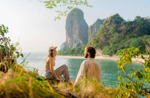 woman and man sitting on cliff on the background of railey bay - travel stock pictures, royalty-free photos & images