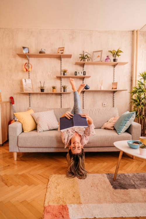 woman at home lying on sofa and reading book - home decoration stock pictures, royalty-free photos & images