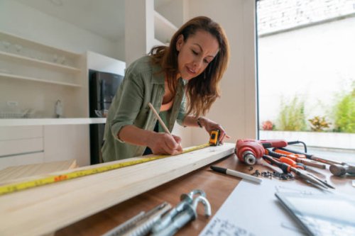 woman at home working on a diy project and measuring a piece of wood - home decoration stock pictures, royalty-free photos & images