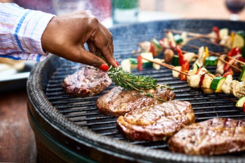 woman basting meat on barbecue with fresh herbs - food stock pictures, royalty-free photos & images