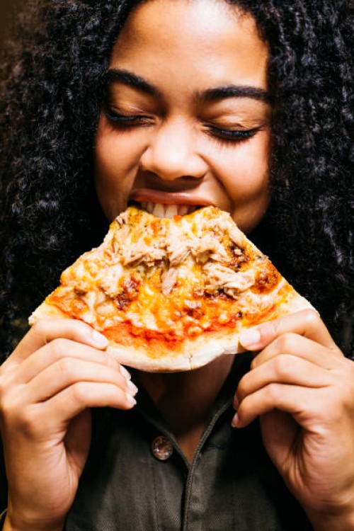 woman biting a slice of a pizza - junk food stock pictures, royalty-free photos & images