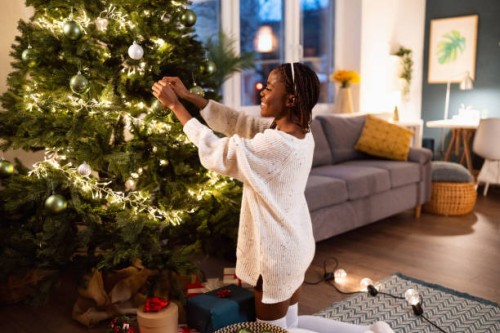 woman black ethnicity decorating a christmas tree - home decoration stock pictures, royalty-free photos & images