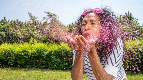 woman blowing pink glitter from palms - garden decoration stockfoto's en -beelden