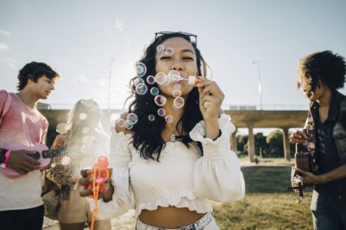 woman blowing soap bubbles while friends playing ukulele during music event - fashion stock pictures, royalty-free photos & images