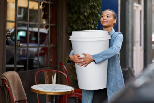 woman carrying large disposable coffee cup outside cafe - junk food stock pictures, royalty-free photos & images