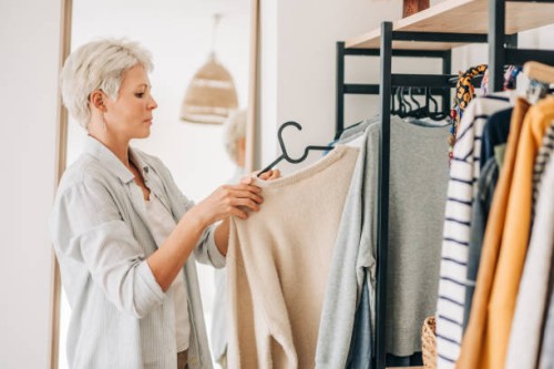 woman choosing dress in front of mirror. - fashion stock pictures, royalty-free photos & images