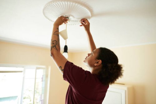woman connecting light bulb on ceiling at home - home decoration stock pictures, royalty-free photos & images