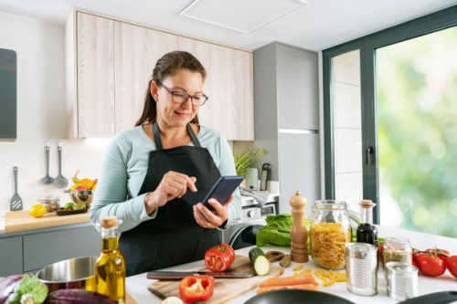 woman cooking and using mobile phone in kitchen - food stock pictures, royalty-free photos & images