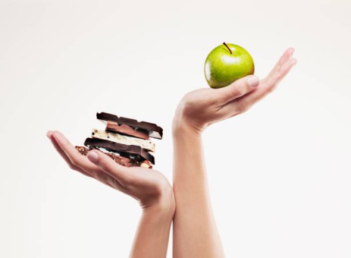 woman cupping green apple above chocolate bars - junk food stock pictures, royalty-free photos & images