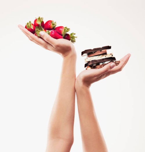 woman cupping strawberries above chocolate bars - junk food stock pictures, royalty-free photos & images