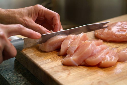 woman cutting raw chicken on a wooden cutting board - food stock pictures, royalty-free photos & images