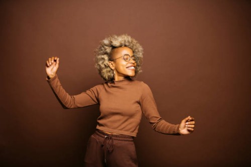 woman dancing against a brown background - fashion stock pictures, royalty-free photos & images