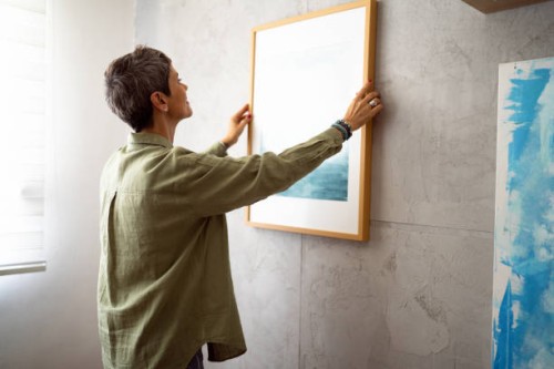 woman decorating her home with a new painting - home decoration stock pictures, royalty-free photos & images