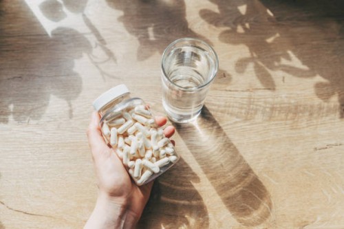 woman doctor nutritionist hands in white shirt with omega 3, vitamin d capsules with green vegan food. the doctor prescribes a prescription for medicines and vitamins at the clinic - food stock pictures, royalty-free photos &