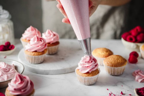 woman doing icing on cupcakes with pink whipped cream - home decoration stock pictures, royalty-free photos & images