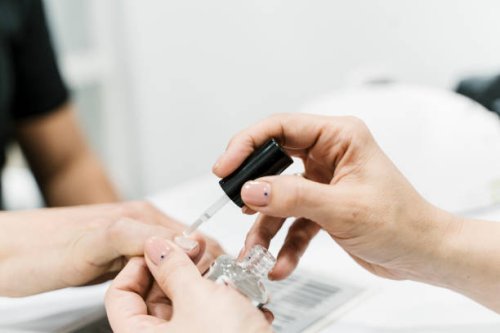woman doing the nails of a modern man in a nail salon - nails art stock pictures, royalty-free photos & images