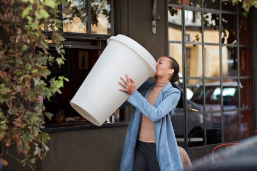woman drinking coffee from large disposable cup at take away counter of cafe - coffee stock pictures, royalty-free photos & images