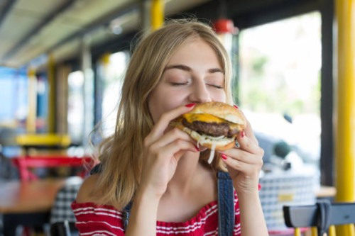 woman eating a hamburger - junk food stock pictures, royalty-free photos & images