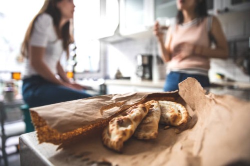 woman eating empanada at home - junk food stock pictures, royalty-free photos & images