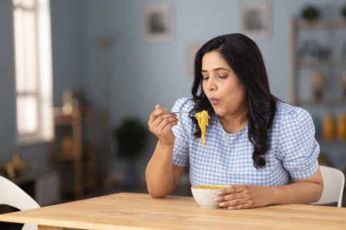 woman eating hot and spicy noodle at home stock photo - junk food stock pictures, royalty-free photos & images
